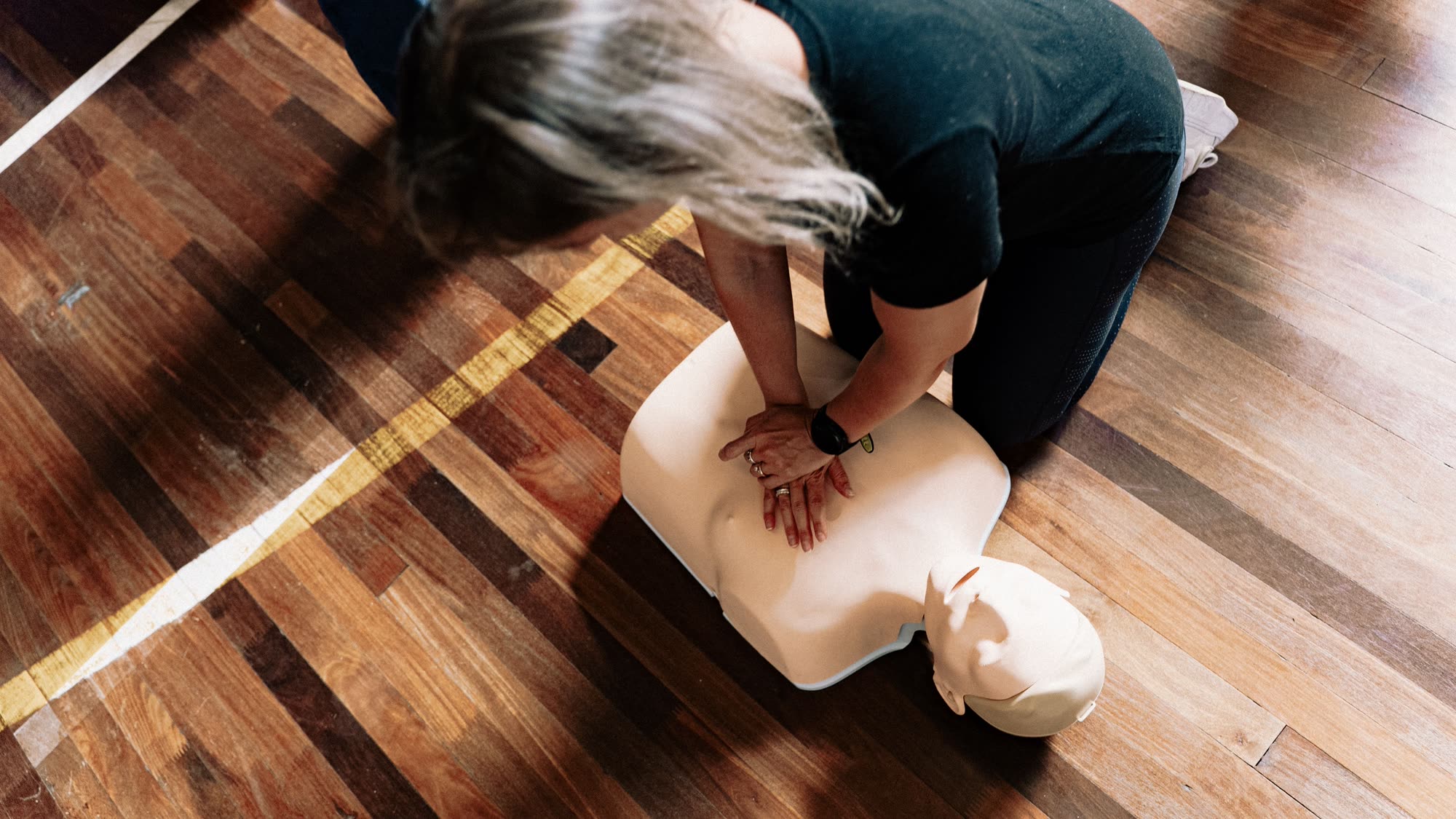 Instructor performing chest compressions on a CPR training manikin